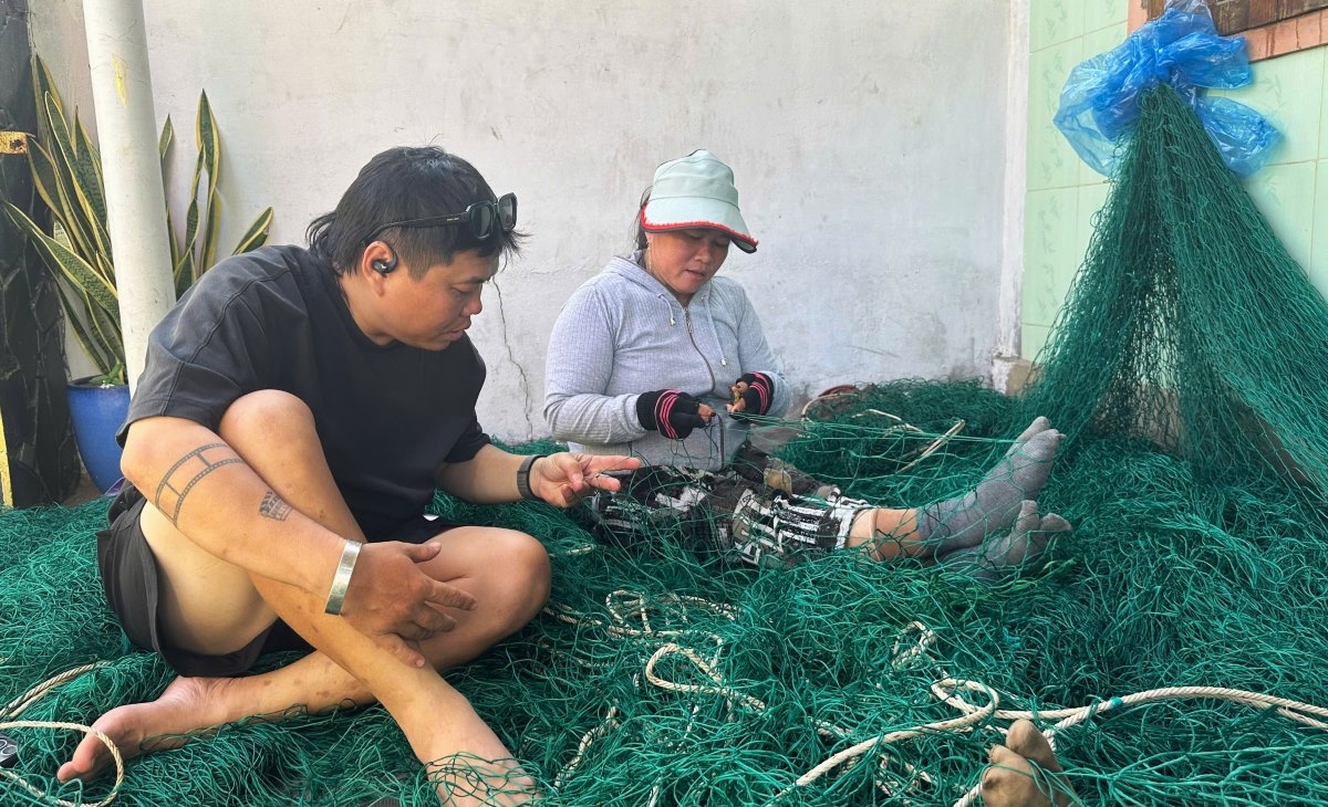 Visitors try their hand at net weaving in Lang Lo village. (Photo: Dinh Tuan)