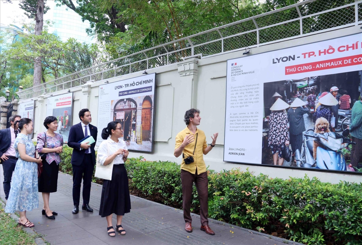 Le photographe Adrien Jean (à droite) présente son travail lors de l'exposition «Lyon – Hô Chi Minh-Ville». Photo: VNA