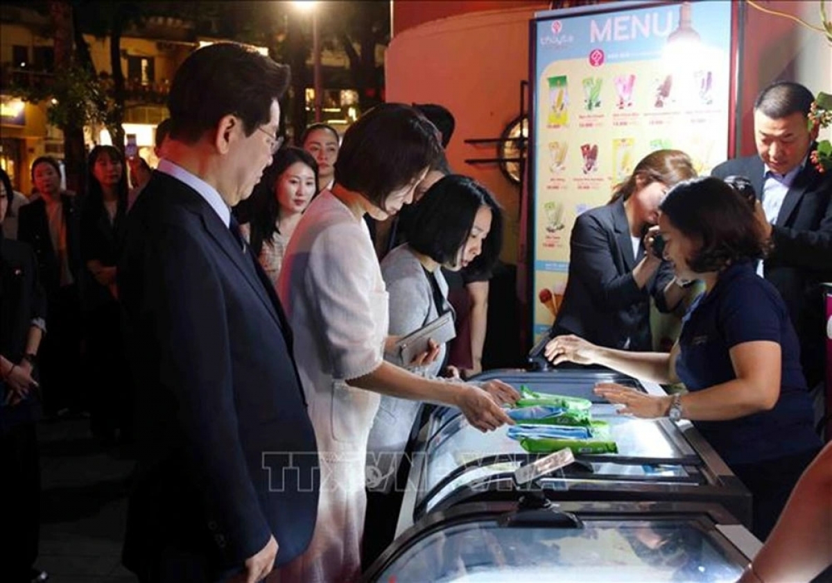 호안끼엠 호수 인근에서 발걸음을 멈추고 투이따(Thủy Tạ, 하노이의 유명한 전통 아이스크림 브랜드) 아이스크림을 구매하는 이재명 대통령 내외 (사진: 베트남 통신사)