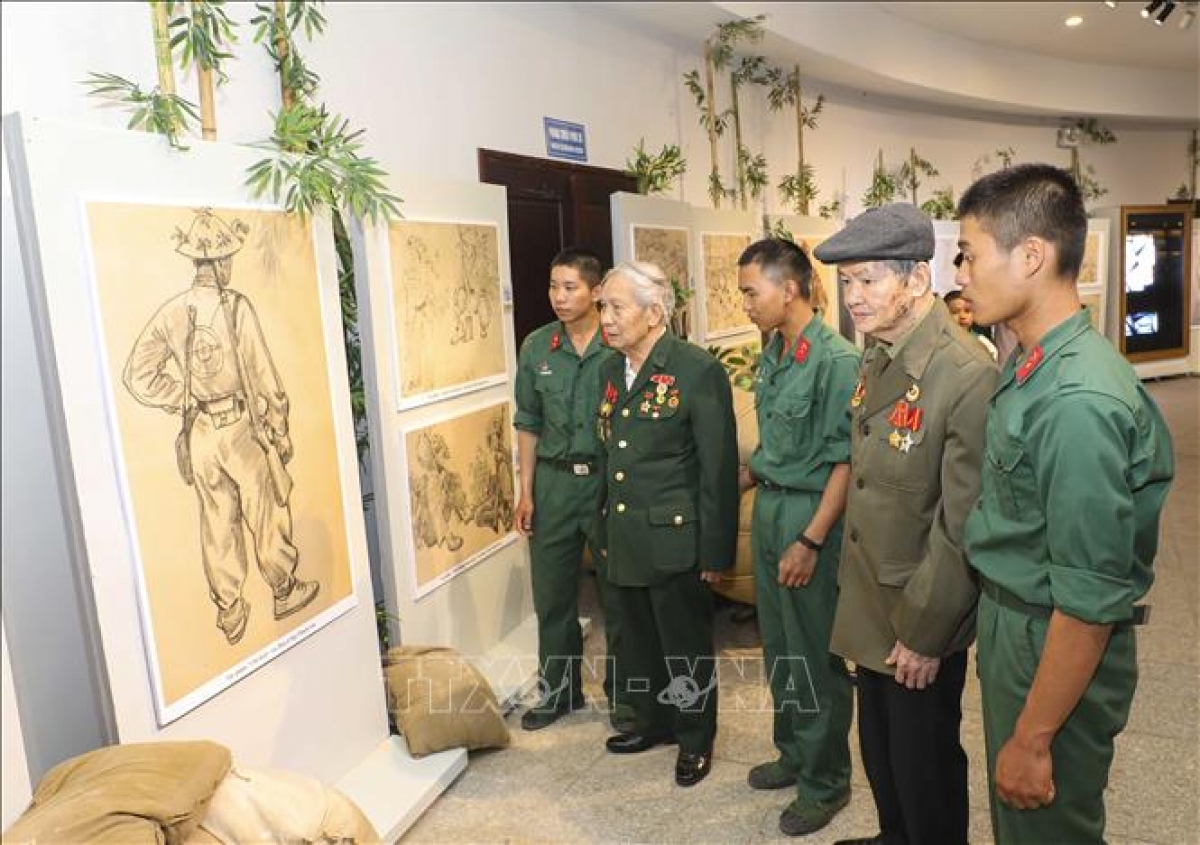 Veteranos de guerra y jóvenes soldados recorren la exposición. Foto: baotintuc.vn