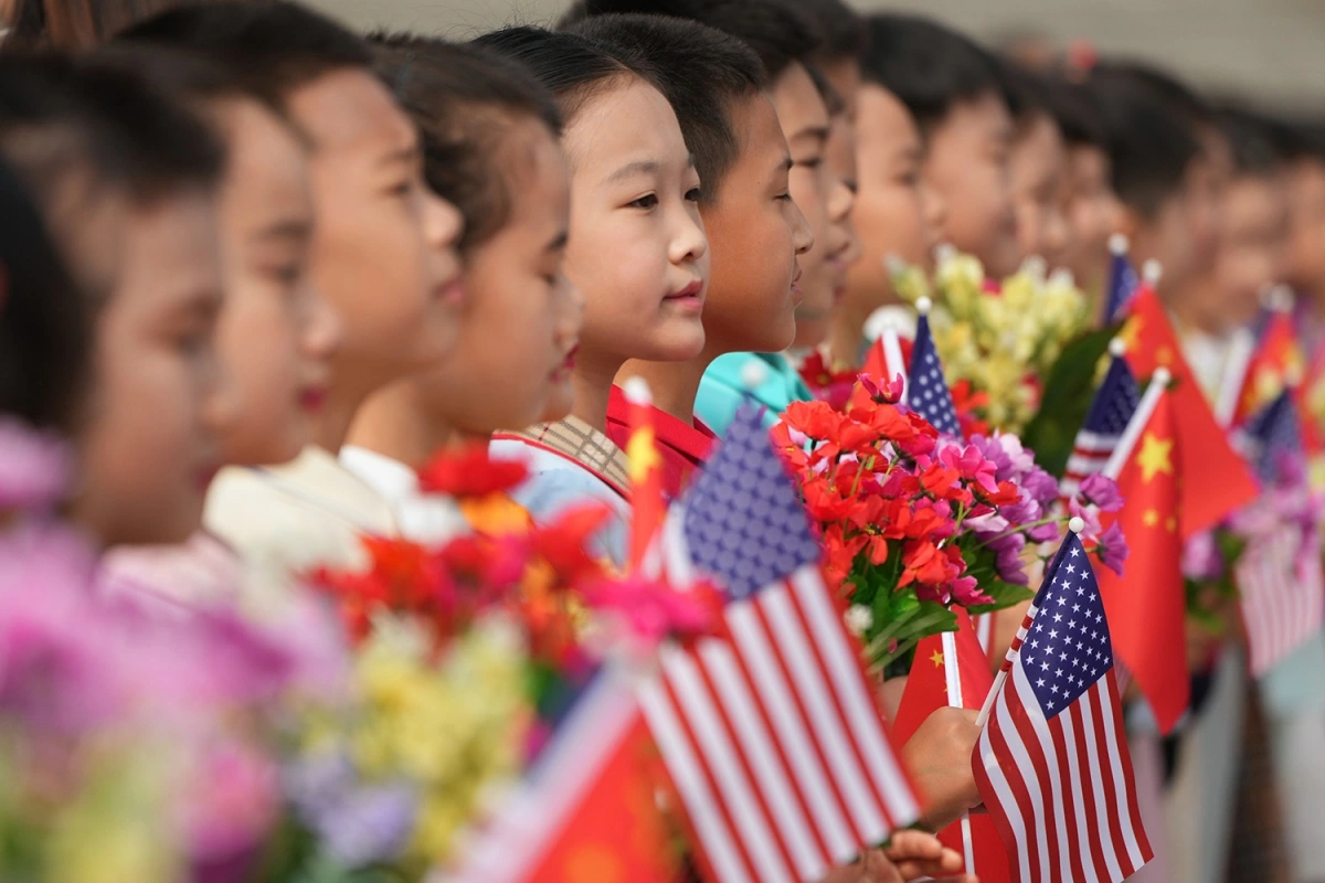 Các em nhỏ cầm cờ Mỹ và Trung Quốc chào đón Tổng thống Mỹ Donald Trump. Ảnh: AP