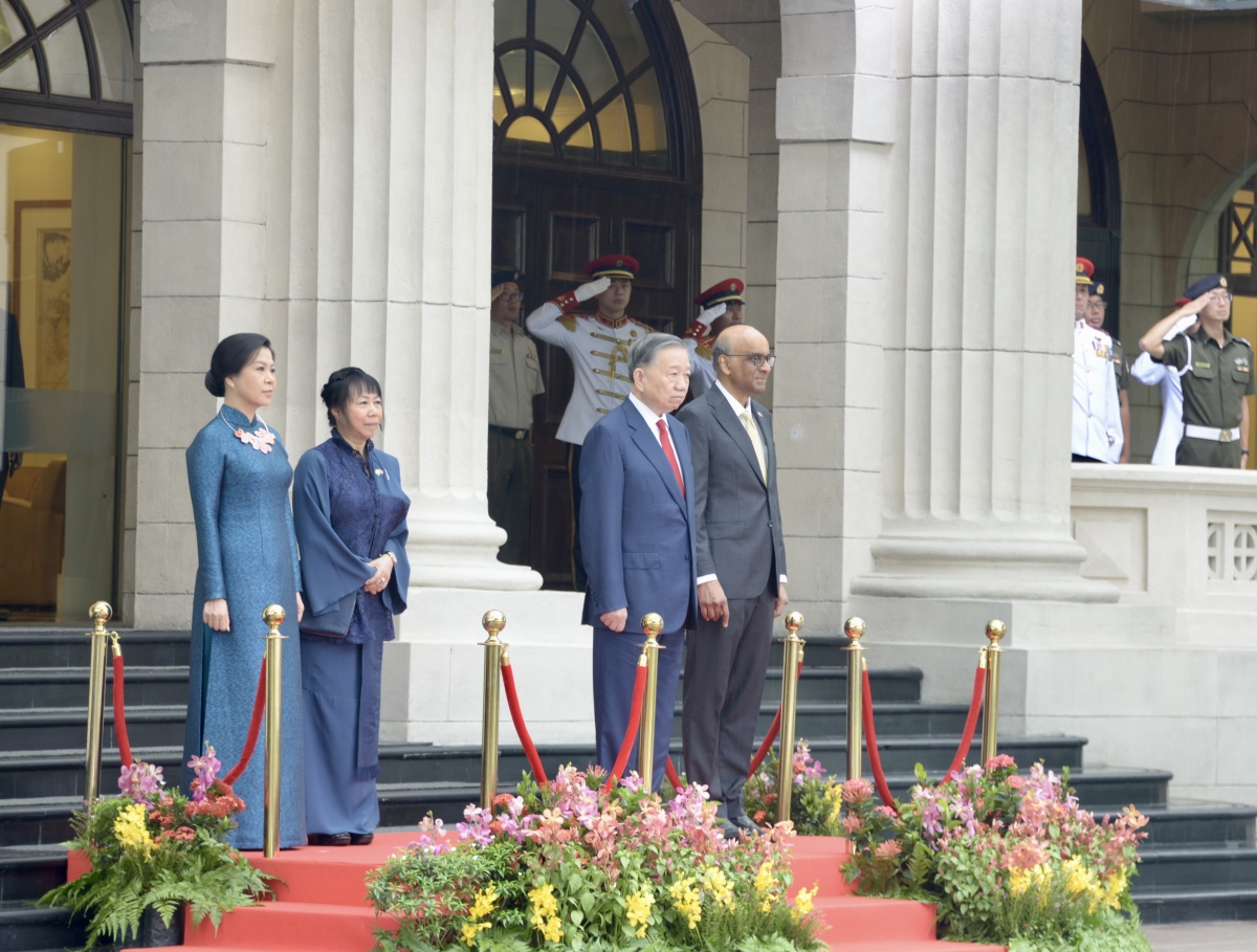 Sekjen sekaligus Presiden To Lam serta Presiden Singapura berdiri di podium kehormatan, sementara band militer memainkan lagu kebangsaan Vietnam dan Singapura. Foto: VOV