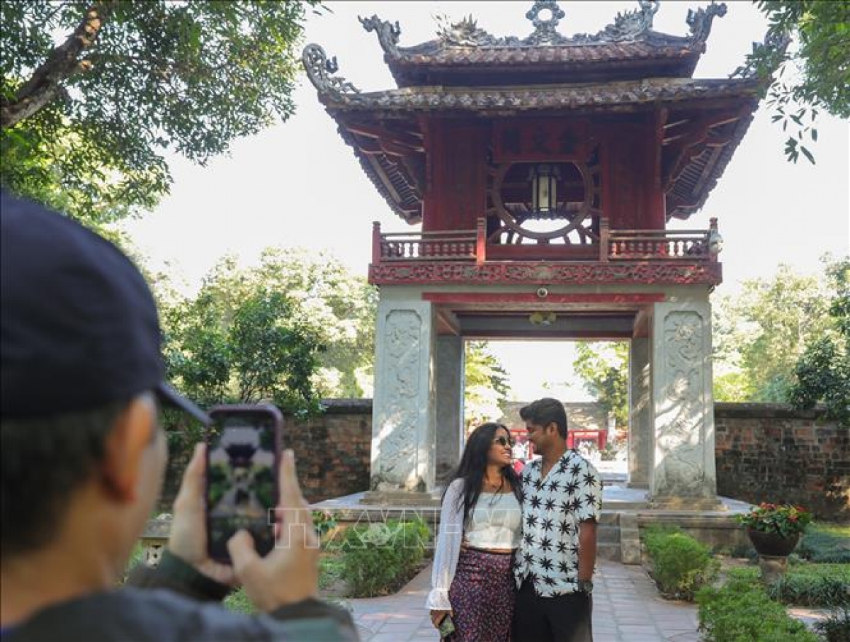 Dos turistas extranjeros toman fotografías en Khue Van Cac, símbolo de Hanói. Foto: Hoang Hieu/VNA