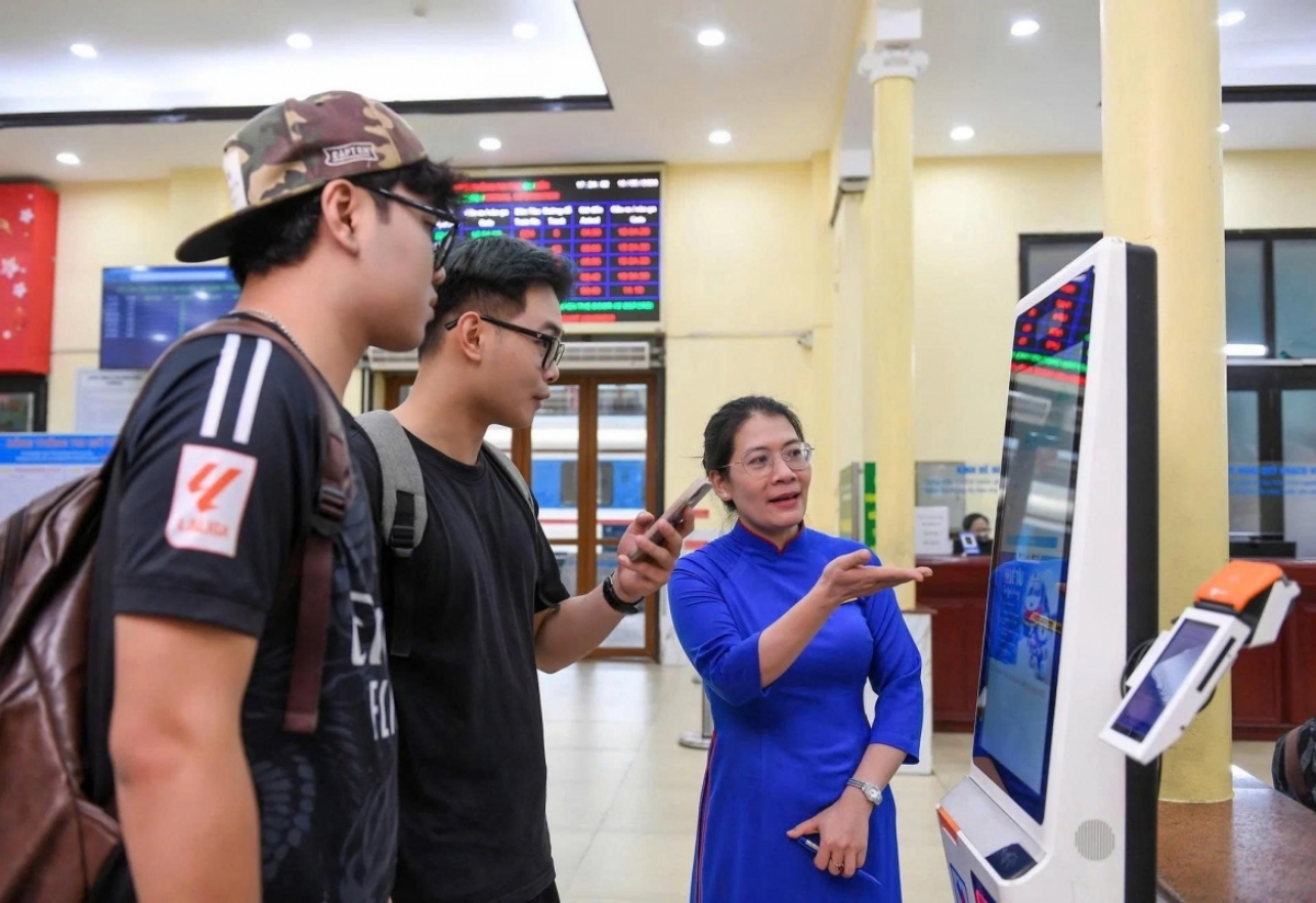 Two young passengers are guided through looking up routes, train schedules, and buying a train ticket. (Photo: VOV)