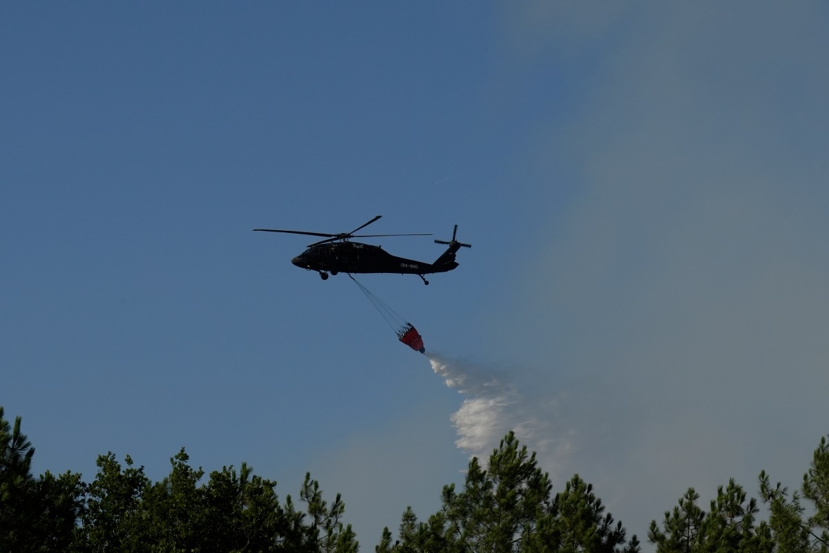 Un hélicoptère Black Hawk déverse de l’eau à l’aide d’un réservoir suspendu sur un incendie près de Lacanau, alors que de violents feux de forêt ravagent les environs de Bordeaux, en France, le 27 juillet 2026.  Photo: AP/Baz Ratner