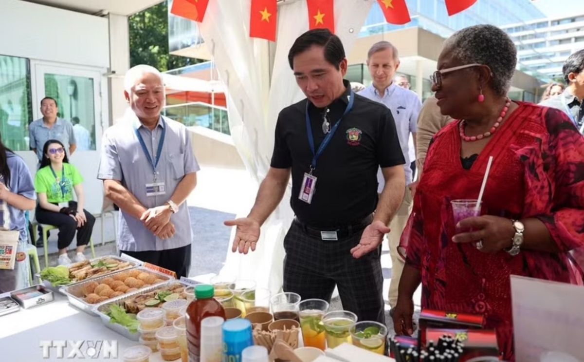 Konselor Quang Huy (berbaju hitam) memperkenalkan gerai Vietnam kepada Direktur Jenderal WTO Ngozi Okonjo-Iweala. Foto: Anh Hien/VNA