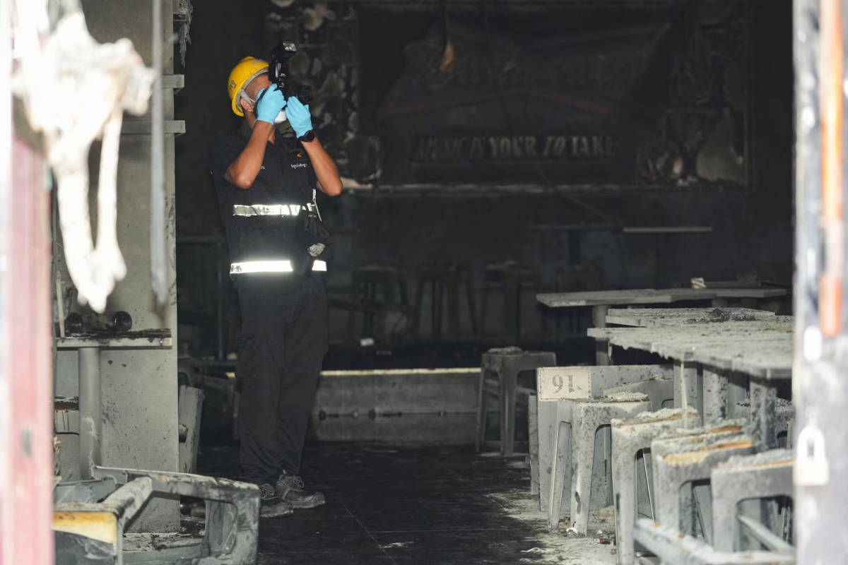 La police scientifique photographie la scène de l'incendie mortel dans un bar à Bangkok, en Thaïlande, le 13 juillet 2026. Photo: REUTERS/Arnun Chonmahatrakool