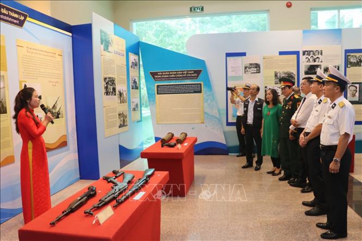Delegates listens to a presentation on displayed items at the exhibition. (Photo: VNA)