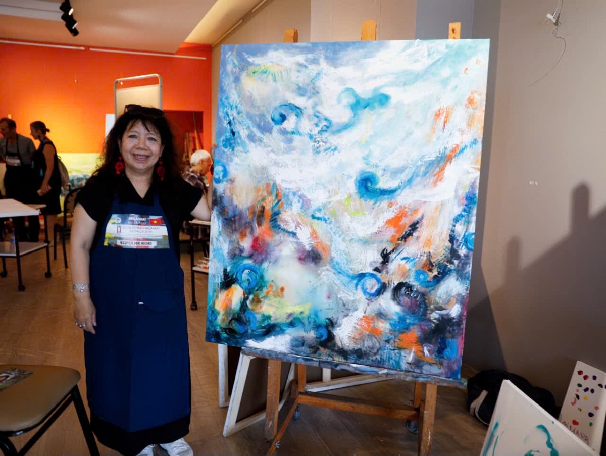 Họa sĩ Nguyễn Mai Hương cùng bức tranh Dòng chảy (Flow) vừa hoàn thành trong xưởng vẽ. Bức tranh sẽ được lưu giữ trong bộ sưu tập nghệ thuật của thành phố.