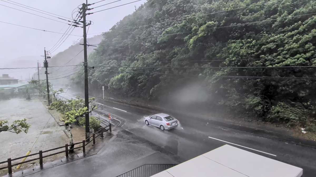 2026年8月7日、鹿児島県奄美市名瀬朝町で、台風ドルフィンが接近する中、強風と豪雨の中を車が走行している。（この画像はソーシャルメディア「@darider5/X/via REUTERS」の動画からの静止画である。）