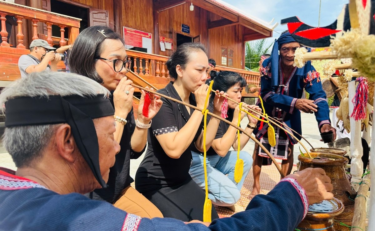 Para wisatawan dan warga desa menikmati minuman arak tradisonal "Cần" dalam Upacara Memohon Hasil Panen masyarakat etnis Ba Na. (Foto: Le Biet/VOV Tay Nguyen)
