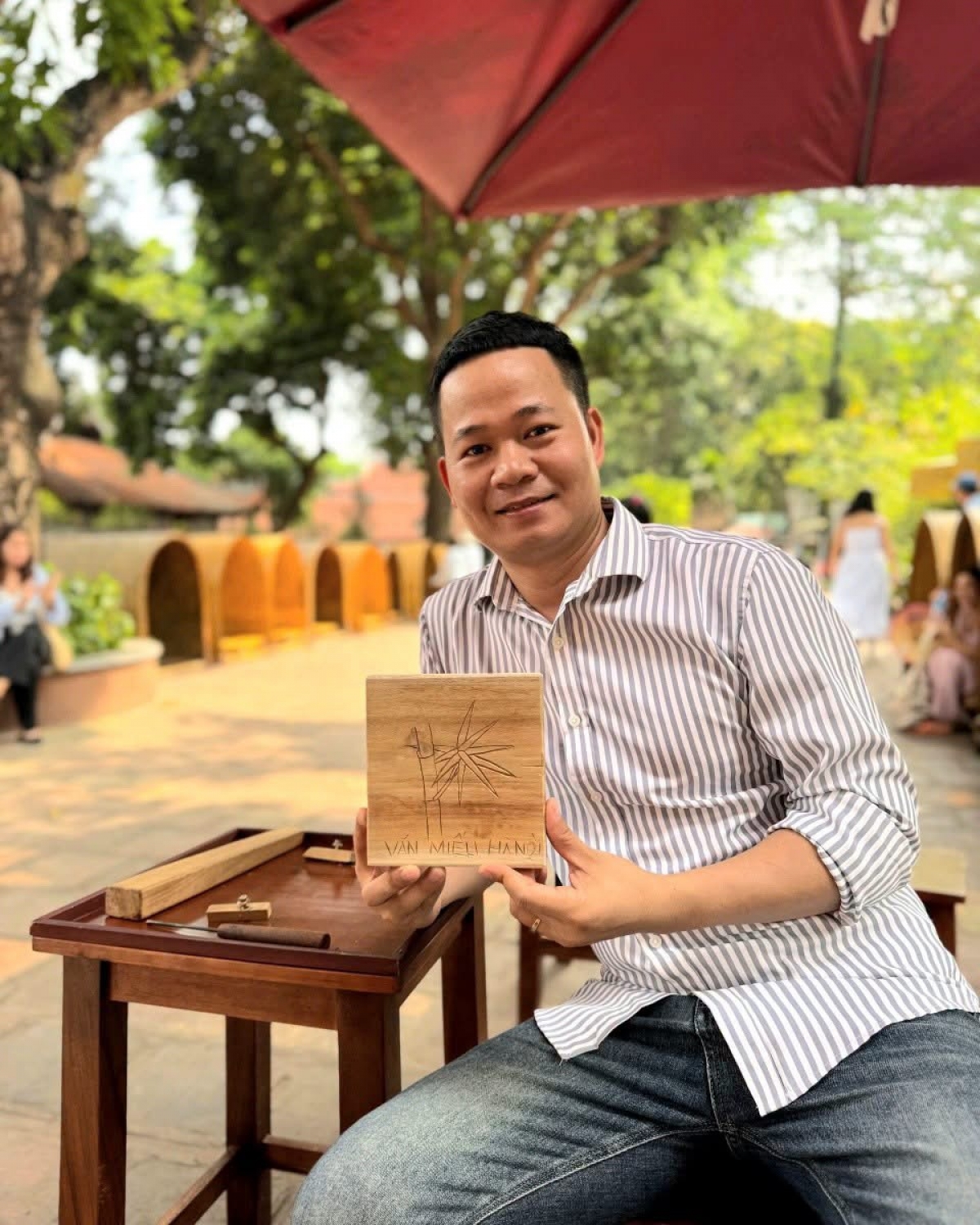 L’artisan Bùi Trong Quân et son œuvre modèle lors de l’atelier «Đưa nghề ra phố». Photo: Tranh gỗ Bùi Gia
