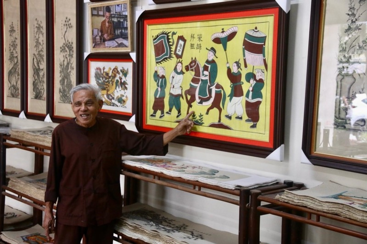 Artisan Nguyen Dang Che and his Dong Ho paintings. (Photo: vusta.vn)