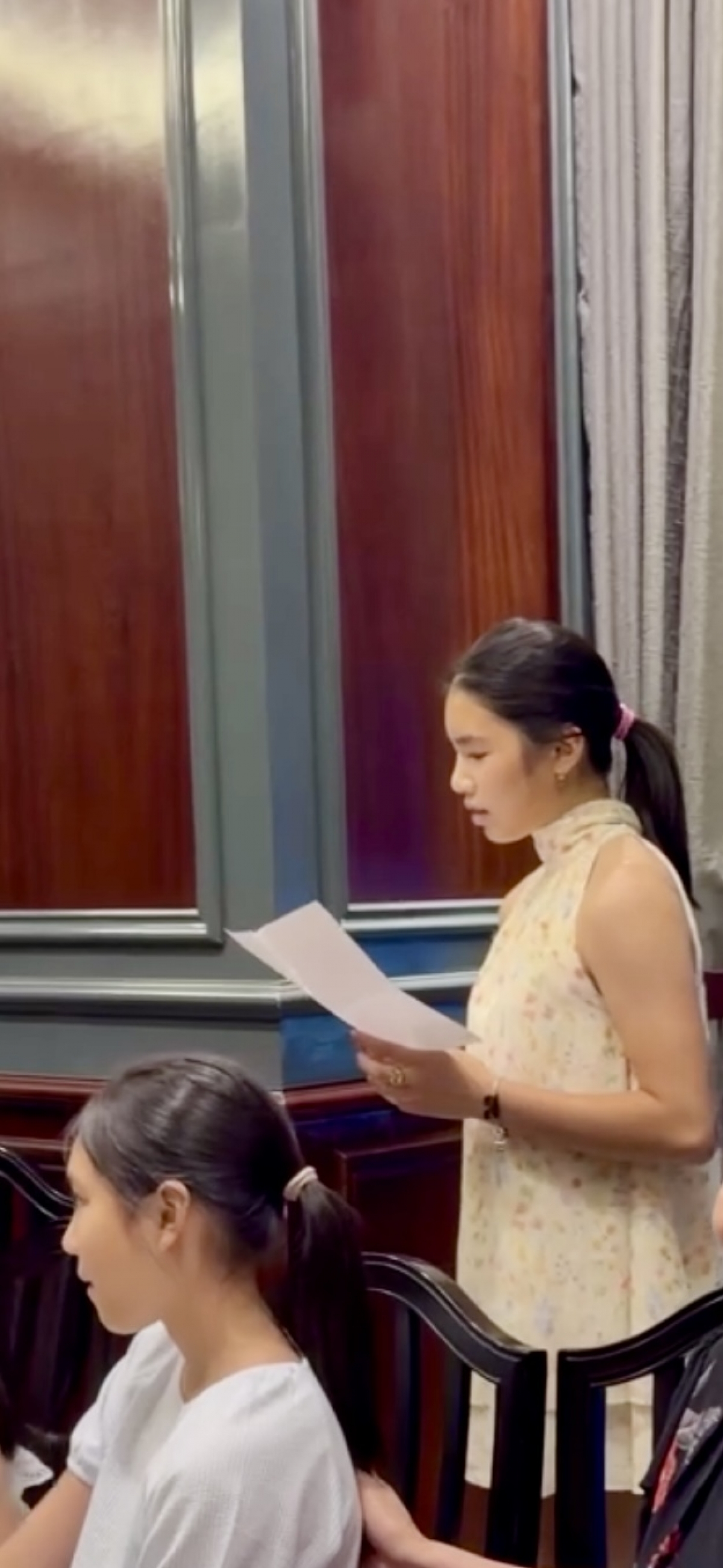 Pham Thanh Mai reads a thank-you note at her party with her family in Vietnam. 