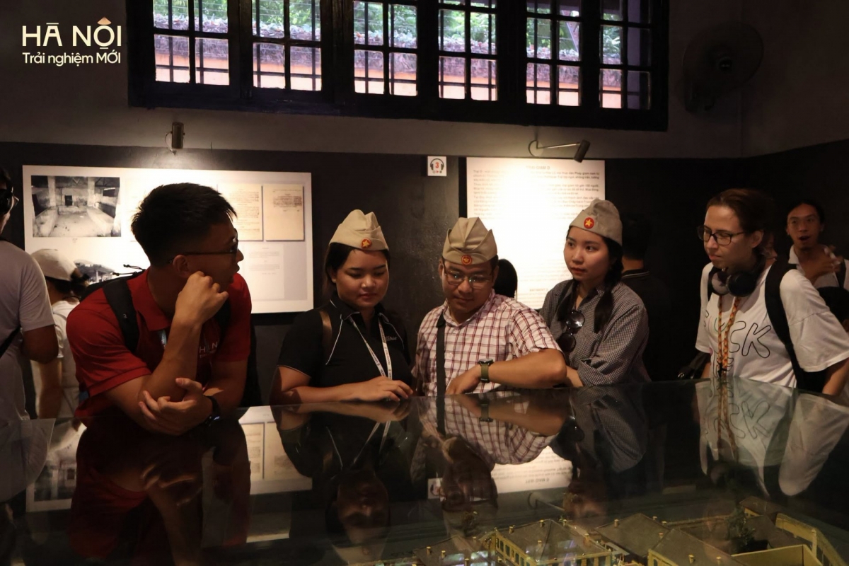 Peserta Walking Tour (bạu merah) memperkenalkan kepada wisatawan tentang benda-benda dalam sebuah pameran (Foto: Hanoi -Pengalaman baru)