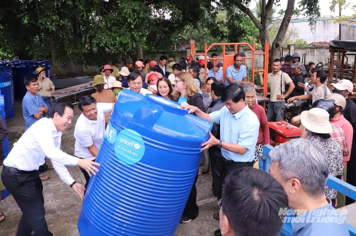 El viceministro Nguyen Hoang Hiep, acompañado de autoridades locales, representantes de UNICEF y vecinos de la zona, participa en la carga de los depósitos de agua en un vehículo. Foto: Trung Tan