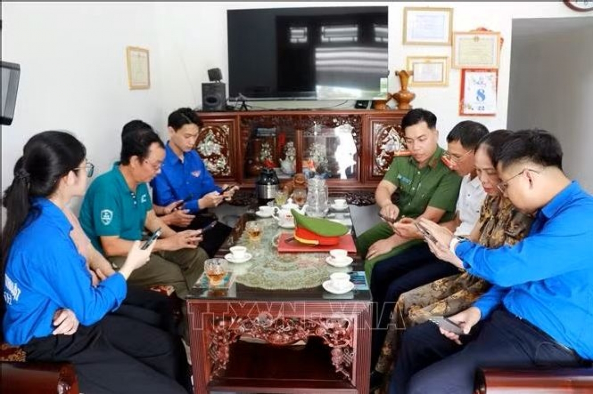 Des policiers et des membres de l’Union de la jeunesse du quartier de Thiên Truong (Ninh Binh) sensibilisent les habitants et les guident pour rejoindre le groupe Zalo consacré à la sécurité et à l’ordre public. Photo: Nguyên Lành/TTXVN