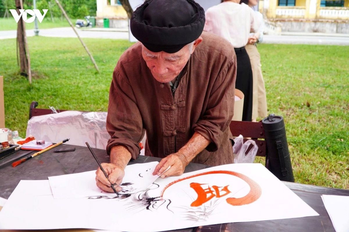 Ông Hồ Viết Sanh, ở xã Đại Đồng, thành phố Đà Nẵng viết thư pháp, sáng tác các tác phẩm thư họa tặng du khách. Ảnh: VOV