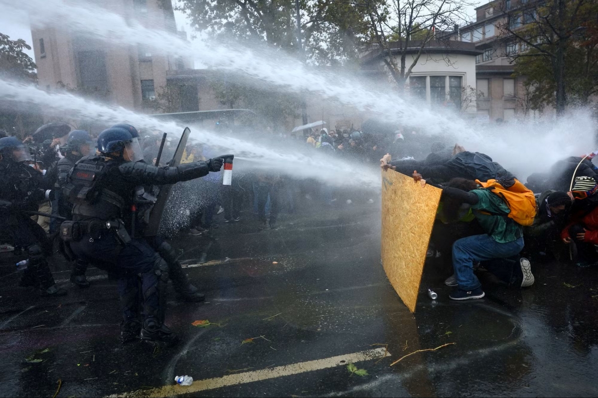 Los manifestantes se resguardan tras tablones de madera contrachapada mientras la policía antidisturbios y la gendarmería francesa utilizan cañones de agua durante una manifestación autorizada y organizada por sindicatos en París el 24 de octubre. Foto: Reuters