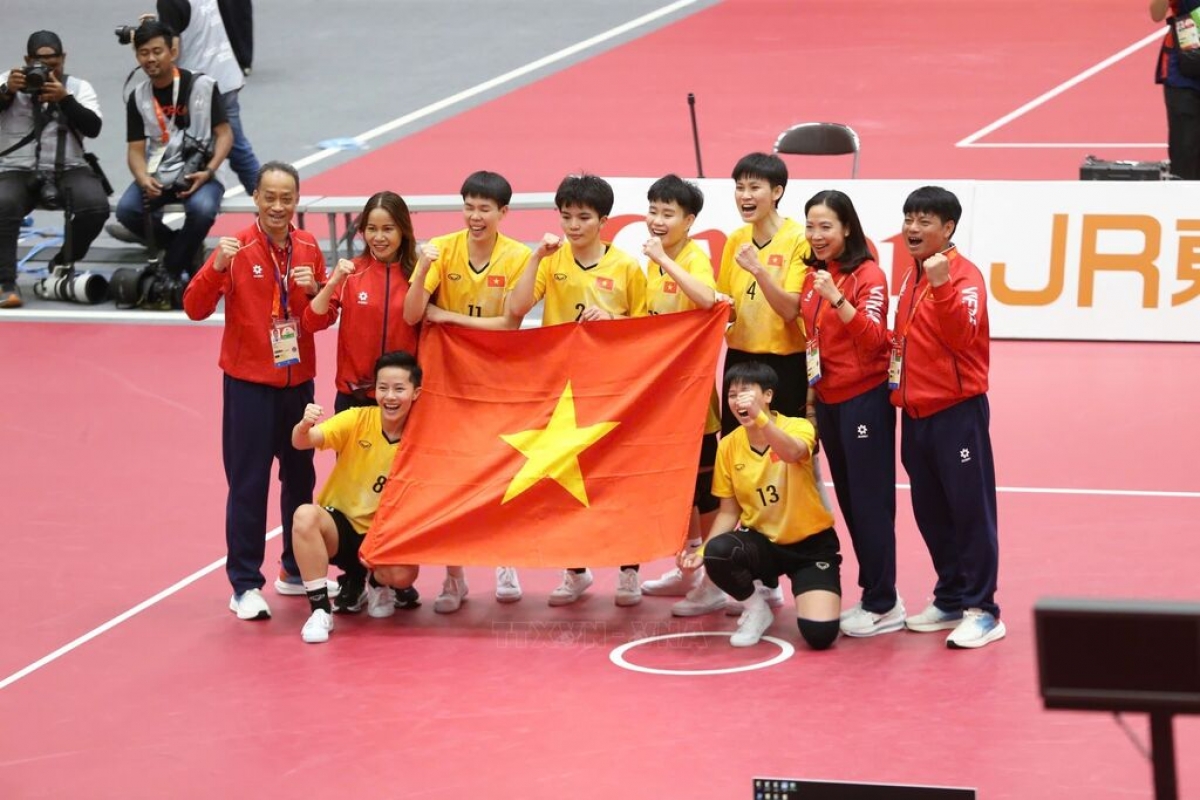 El equipo femenino vietnamita de sepak takraw celebra su victoria con la bandera nacional. Foto: VNA
