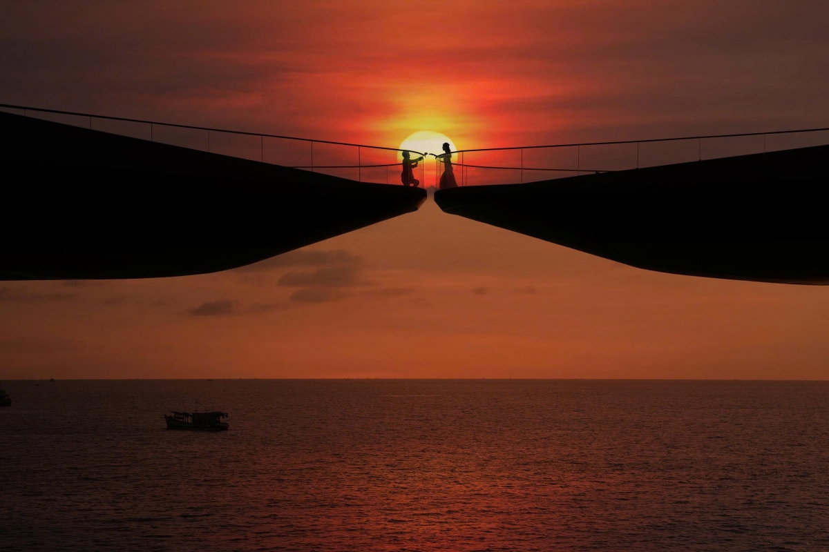 Im leuchtend roten Sonnenuntergang erstrecken sich die beiden Arme der Kussbrücke in Richtung Meer und schaffen eine der eindrucksvollsten Kulissen im Süden von Phu Quoc.