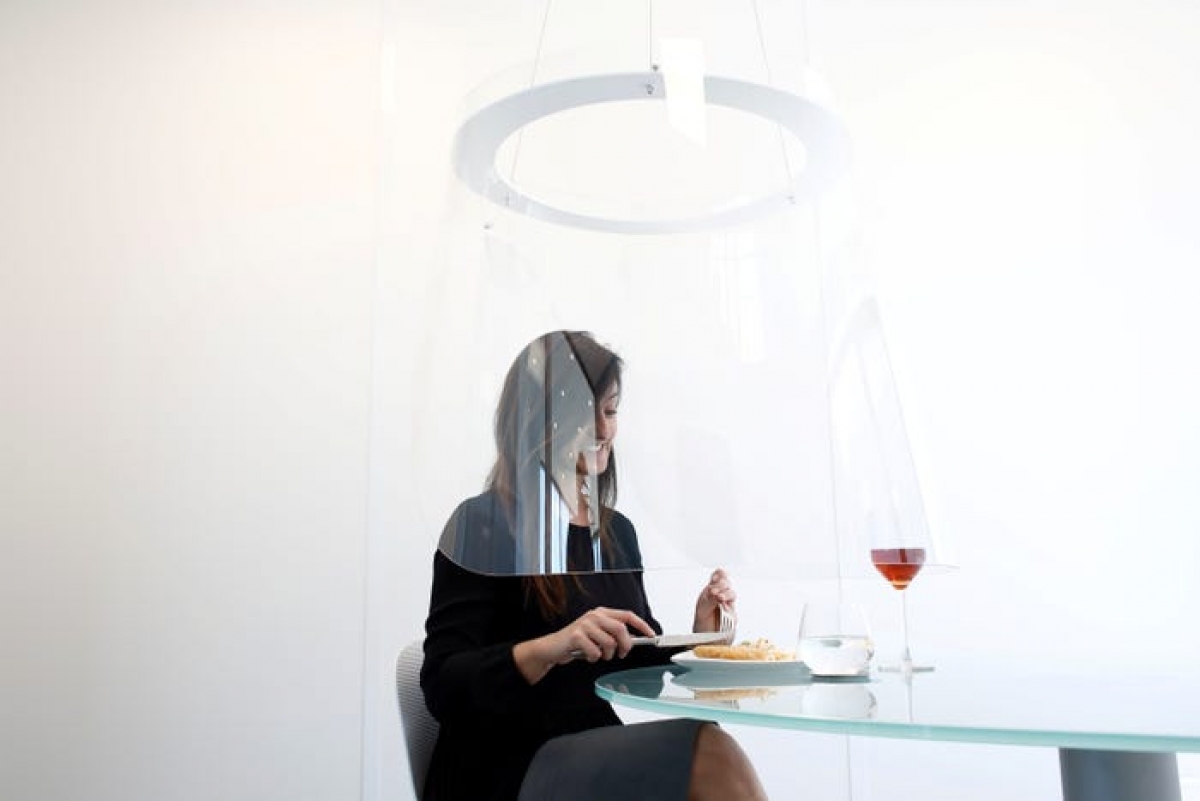 A woman dines in a prototype of the Plex'Eat plexiglass bubble by Christophe Gernigon. (Photo: Reuters/Benoit Tessier)