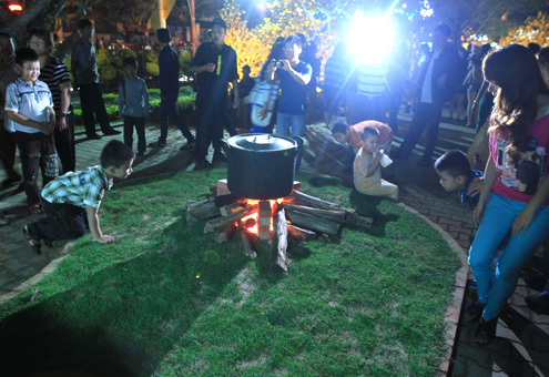 Nhiều em nhỏ tò mò xem mô hình nồi nấu bánh chưng. Với trẻ em ở thành phố, việc được cùng gia đình nấu bánh chưng trong dịp tết rất hiếm hoi.