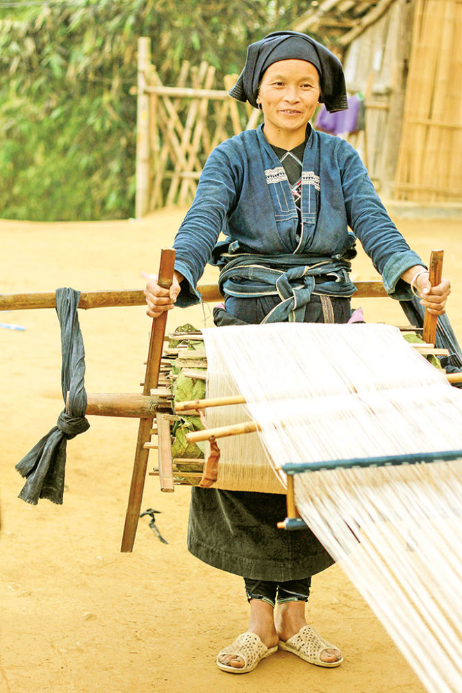 Người phụ nữ dùng tay kéo bánh xe quay vải